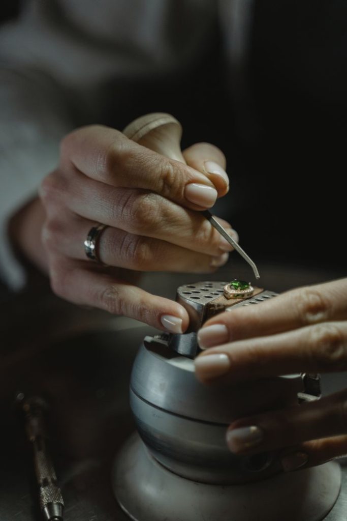 Close-up of a jeweler skillfully crafting an emerald ring, showcasing precision and detail.